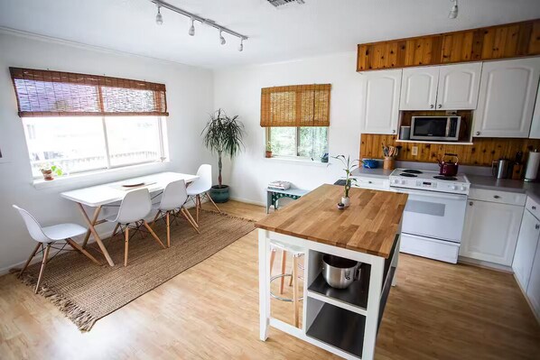 A modern kitchen with white cabinets, a wooden countertop, and a built-in microwave. - Welcome to Sea Perch, a cozy beach box with a large hot tub! (Kill Devil Hills)