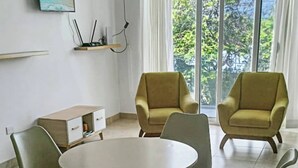 Un comedor con una mesa redonda y seis sillas, un archivador pequeño y un cuadro en la pared.