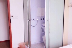 Une salle de bain avec une douche à parois de verre, des toilettes et un lavabo.