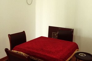 Une chambre avec un lit simple, une petite table et deux chaises.