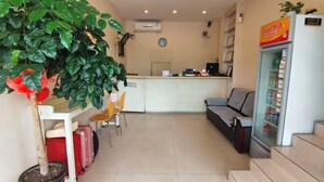 A reception area with a desk, chairs, a refrigerator, and a potted plant.