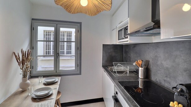A modern kitchen with a black countertop, stainless steel appliances, and a large window with a view. - Le Van Gogh - In the Heart of Arles (Arles)