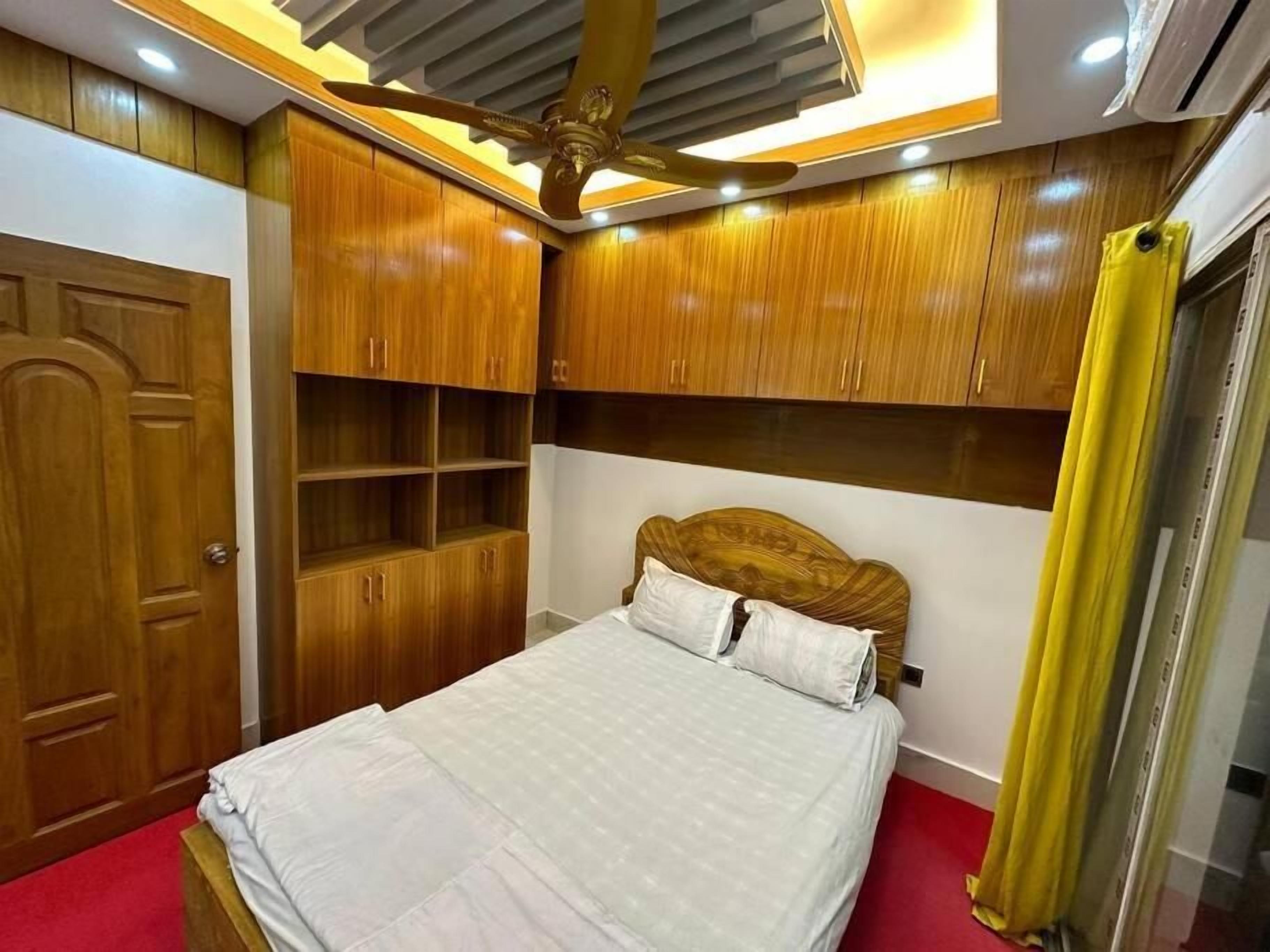 A bedroom with a bed, wooden wardrobe, and built-in shelves.
