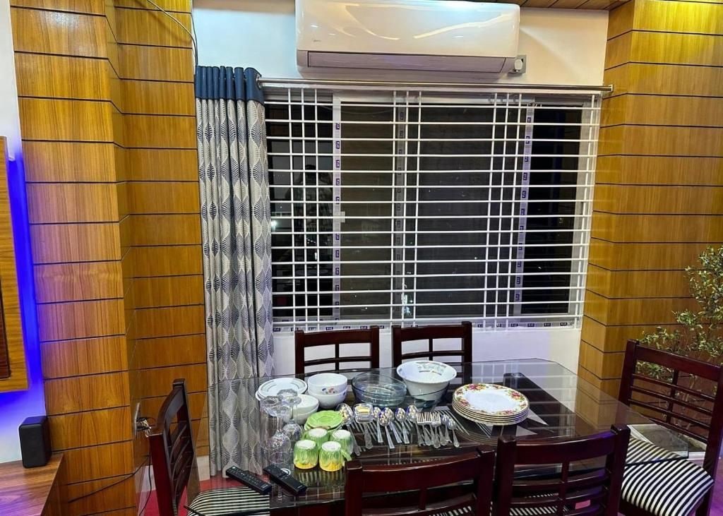A dining area with a glass table, chairs, and a window with metal bars.