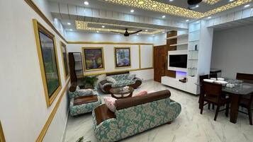 A modern living room with a sofa set, a dining table, and a TV.
