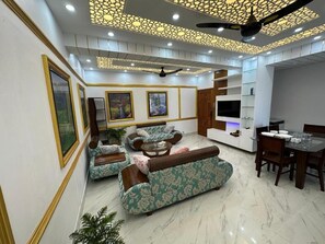 A modern living room with a sofa set, a dining table, and a TV. - Garden view villa  (Rajshahi)