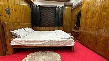 Un dormitorio ordenado con una cama grande, un armario de madera y una alfombra roja.