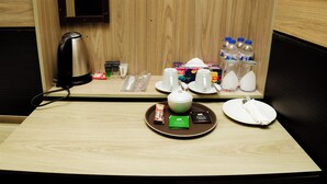 Habitación de hotel con un armario de madera, una tetera, una bandeja con bolsitas de té, un plato y una servilleta.