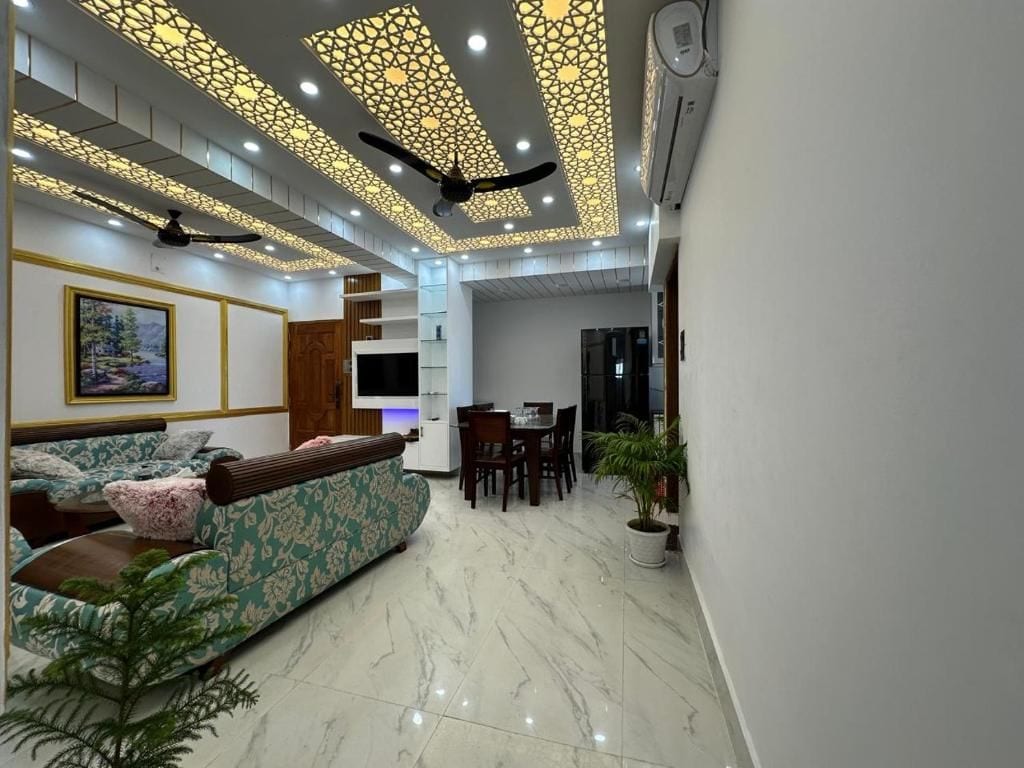 A modern living room with a sofa, dining table, and ceiling with decorative panels.
