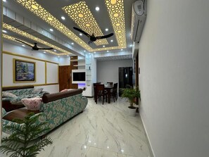 Een moderne woonkamer met een bank, een eettafel en een plafond met decoratieve panelen.