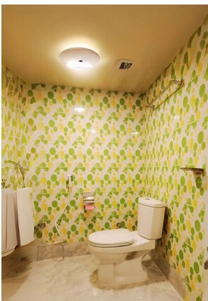 Un baño con inodoro, ducha y pared con diseño.