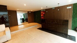Un moderno vestíbulo con mostrador de recepción, zona de estar y escalera que lleva a los pisos superiores.