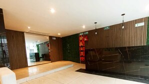 Un vestíbulo moderno con una recepción, un sofá de cuero negro y una pared verde con indicaciones.