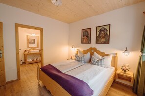 A bedroom with a wooden bed, two bedside tables, a nightstand with a vase, and a wooden wardrobe. - Chalet Near Lake Grundlsee & Ski Lift (Grundlsee)