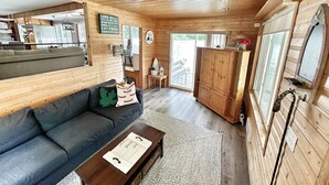 Interior acogedor de una cabaña con techo de madera, un sofá, una mesa de centro y un mueble grande.