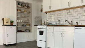 Una cocina con armarios blancos, estufa y lavavajillas.
