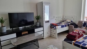 A compact living space with a TV, a bed, a sofa, and a small table. - Unique Hostel Dubai (Dubai)