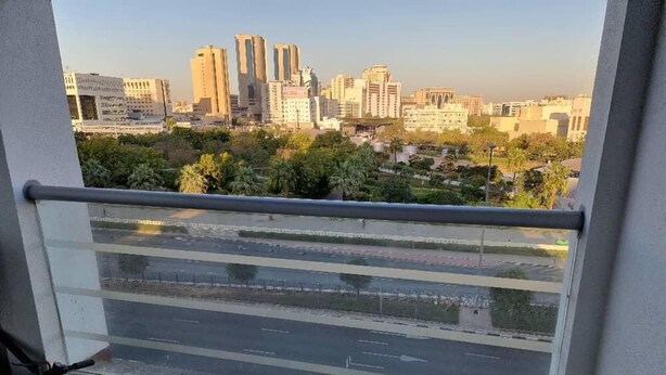 A balcony with a view of a cityscape, including tall buildings and greenery. - Unique Hostel Dubai (Dubai)