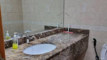 A bathroom with a marble sink, a mirror, and a toilet.