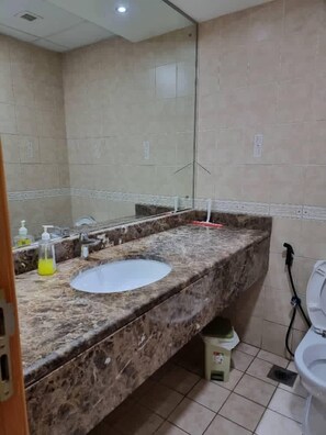 A bathroom with a marble sink, a mirror, and a toilet. - Unique Hostel Dubai (Dubai)