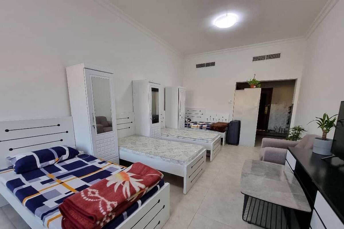 A compact bedroom with a bed, a desk, and a wardrobe.