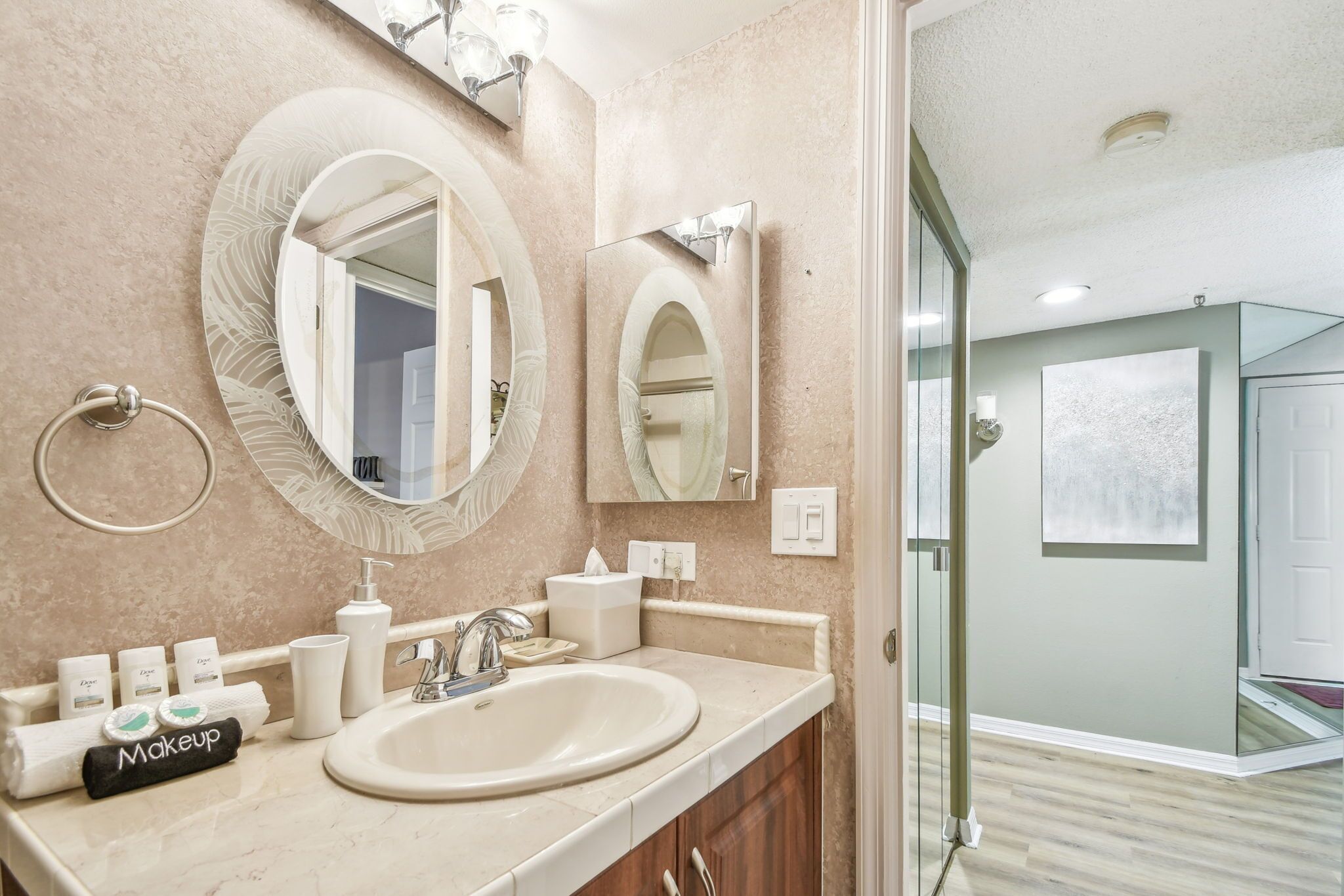 Un bagno con un ampio specchio ovale, un lavandino e un porta asciugamani.