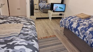 A hotel room with two beds, a television on a stand, a small table, and a door leading to another room. - NightRest Homes Hemel Hempstead 4 Bedroom 2 Toilet (Hemel Hempstead)