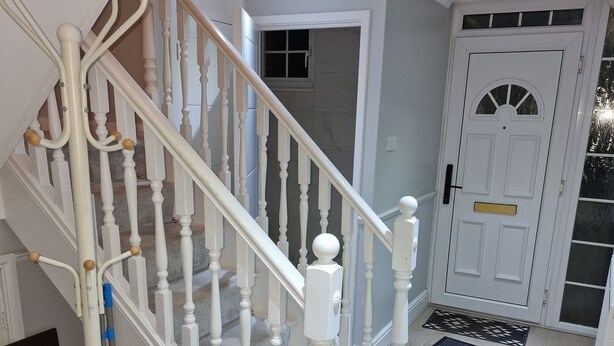 A staircase with white balusters and a handrail, leading to a landing with a door and a window. - NightRest Homes Hemel Hempstead 4 Bedroom 2 Toilet (Hemel Hempstead)