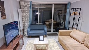 A living room with a TV, sofas, a coffee table, and a patterned rug. - NightRest Homes Hemel Hempstead 4 Bedroom 2 Toilet (Hemel Hempstead)