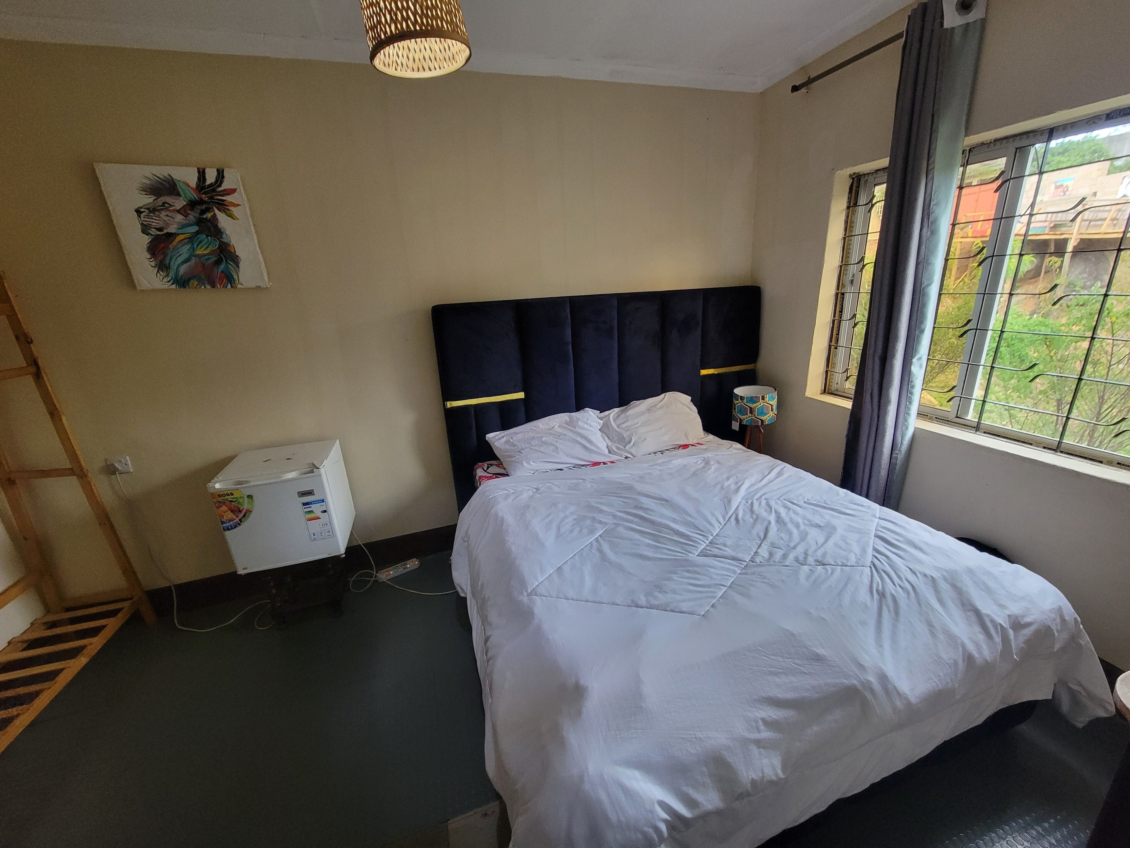 A hotel room with a bed, a desk, a lamp, and a window with a view.