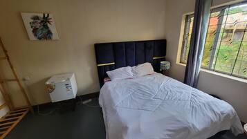 A hotel room with a bed, a desk, a lamp, and a window with a view.