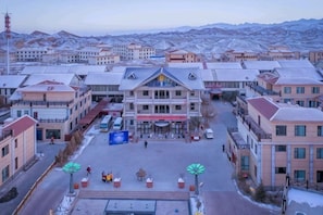 A town square with buildings, a central building with a red sign, and a few people.