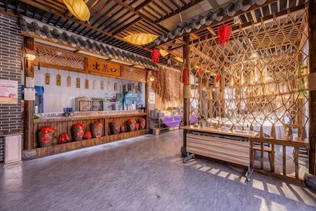A traditional Chinese tea house interior with a wooden counter, tea barrels, and a lattice window.. Shenghua Culture International Hotel