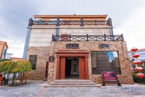 A building with a stone facade, a wooden door, and a sign above the entrance.