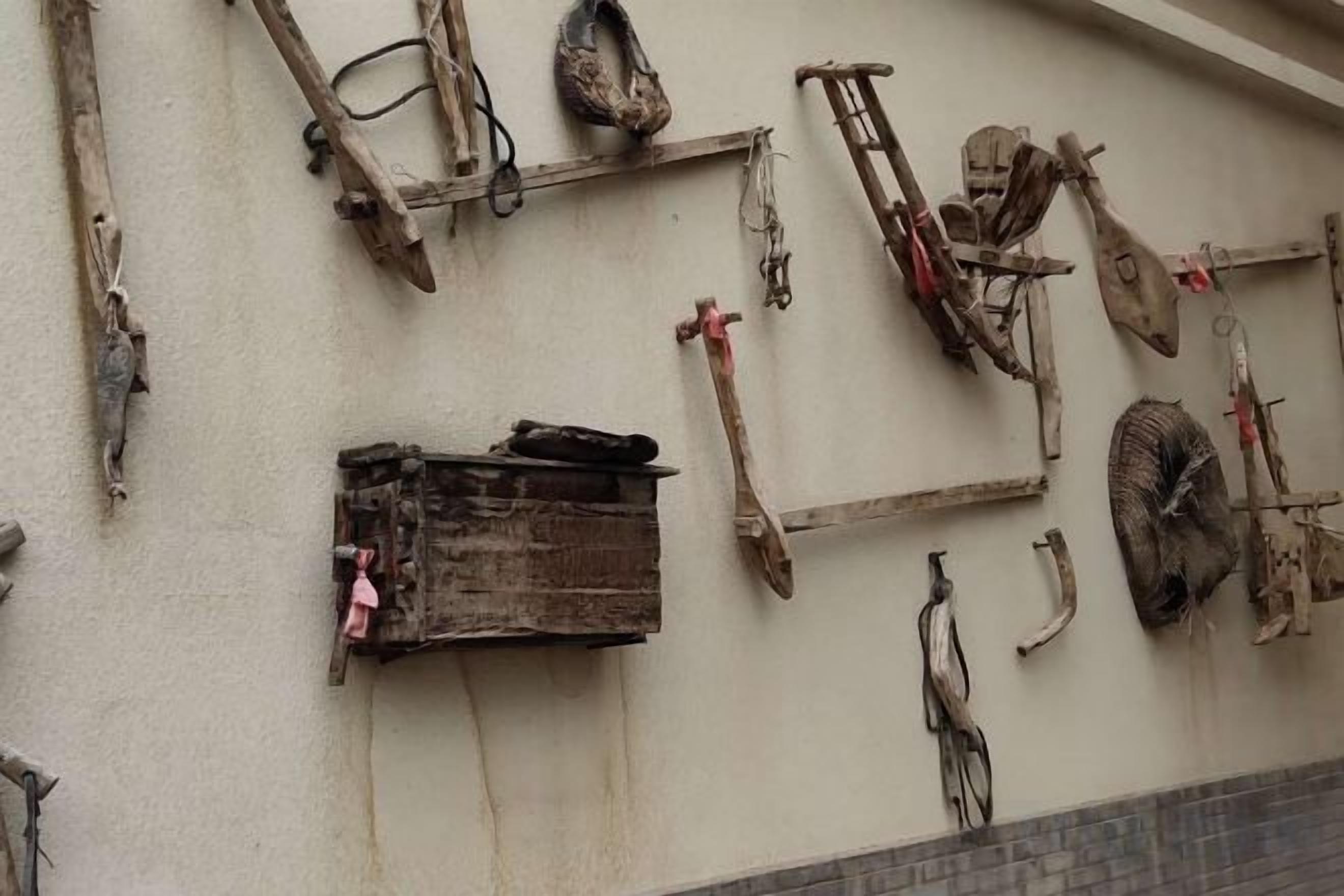 Een muur met diverse gereedschappen en materialen, waaronder een houten doos en verschillende metalen voorwerpen.