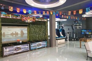 Un área de entretenimiento interior con máquinas de arcade, una pantalla grande y una consola de videojuegos.