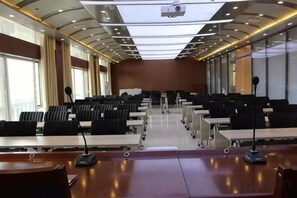 A conference room with rows of tables and chairs, a projector, and a large window. - Shenghua Culture International Hotel (Linze)