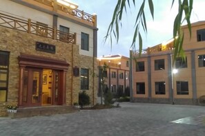 A hotel with a stone facade, multiple windows, and a balcony. - Shenghua Culture International Hotel (Linze)