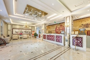 A spacious lobby with a reception desk, seating area, and a chandelier. - Shenghua Culture International Hotel (Linze)
