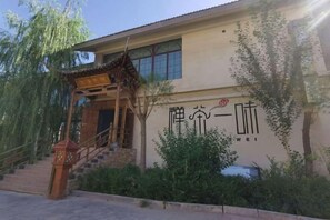 A building with a traditional Chinese architectural style, a staircase leading to the entrance, and a sign with Chinese characters.