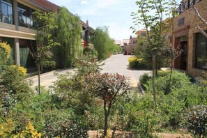 A courtyard with buildings, trees, and a paved walkway. - Shenghua Culture International Hotel (Linze)