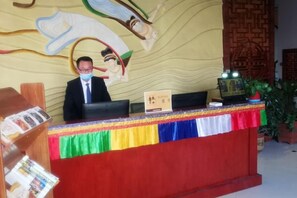 A reception desk with a nameplate, a clock, and a plant. - Shenghua Culture International Hotel (Linze)