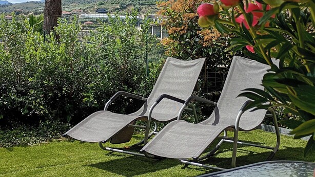 Ein Garten mit Pool, Liegestühlen und Blick auf die Landschaft.