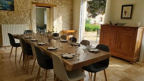 A dining area with a long wooden table set for a meal, surrounded by chairs.