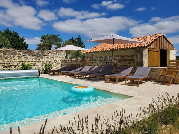 A swimming pool with lounge chairs and a stone wall.