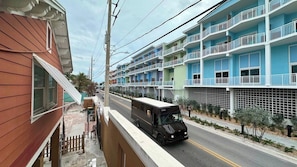 A multi-story building with balconies, a street view, and a parked vehicle.