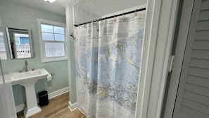 A bathroom with a map-themed shower curtain, a sink, and a window.