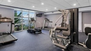 Ein Fitnessraum mit Trainingsgeräten, einem Laufband und einem großen Fenster mit Blick.