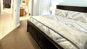 Ein Schlafzimmer mit einem Bett, einem Deckenventilator und einem durch eine offene Tür einsehbaren Badezimmer.