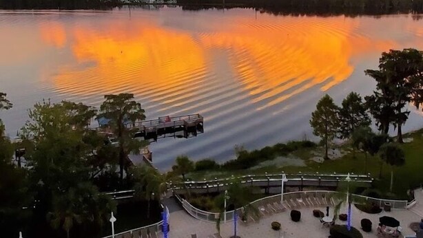 Ein Schwimmbecken mit Blick auf einen Sonnenuntergang über dem Wasser.